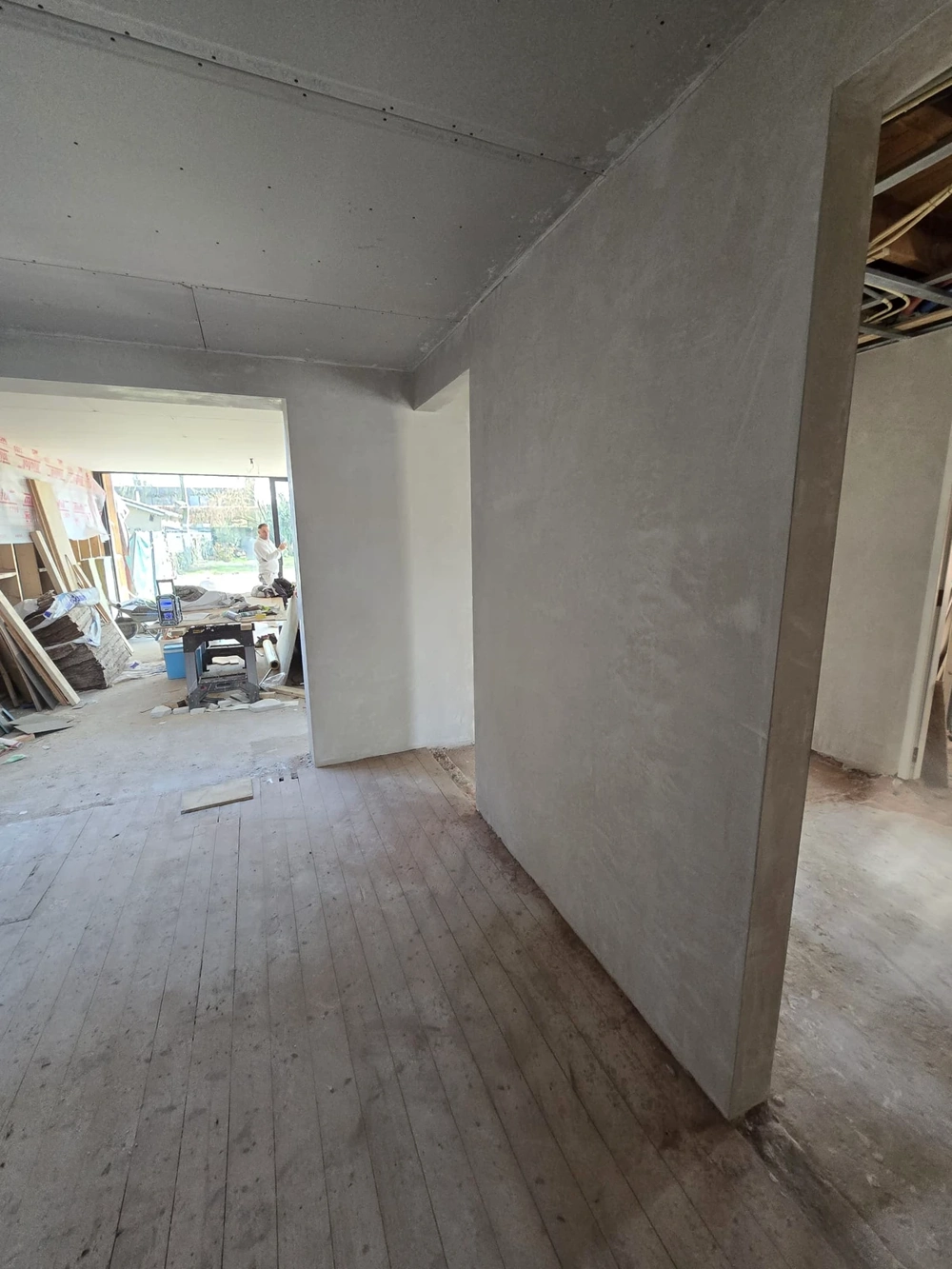 Innenraum mit neu errichteter Trockenbauwand und rohem Dielenboden