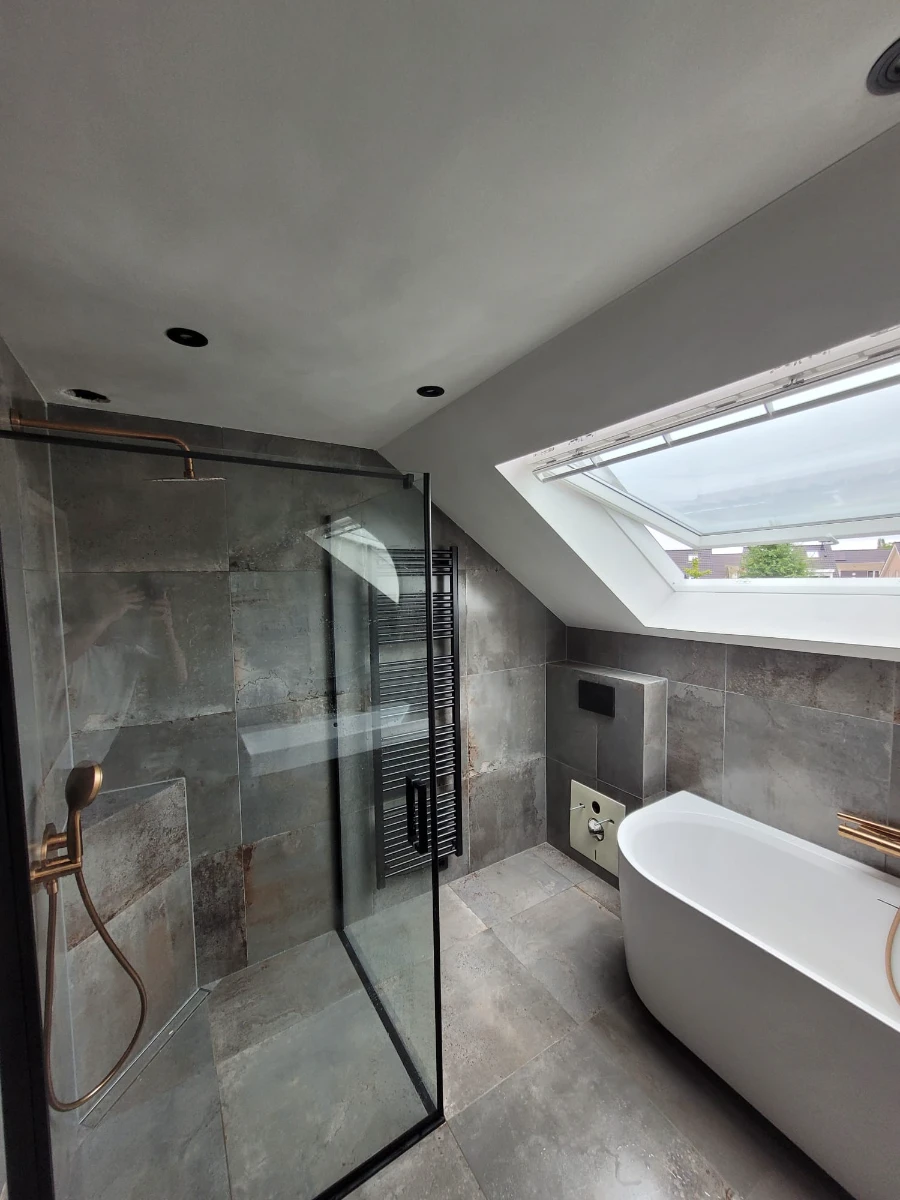 Moderne Badsanierung im Dachgeschoss mit freistehender Badewanne, begehbarer Dusche und grauen Fliesen