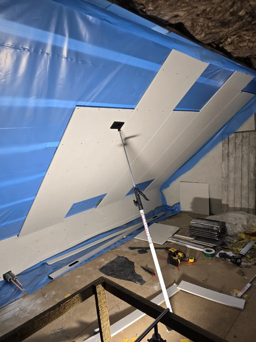Montage von Gipskartonplatten an abgehängter Dachschräge im Trockenbau mit Montageheber und Schutzfolie
