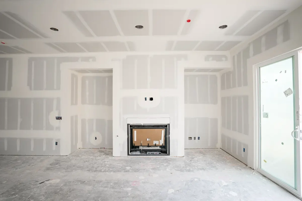 Wohnzimmer-Rohbau mit fertiggestellten Trockenbauwänden, Abklebungen und offener Kaminnische