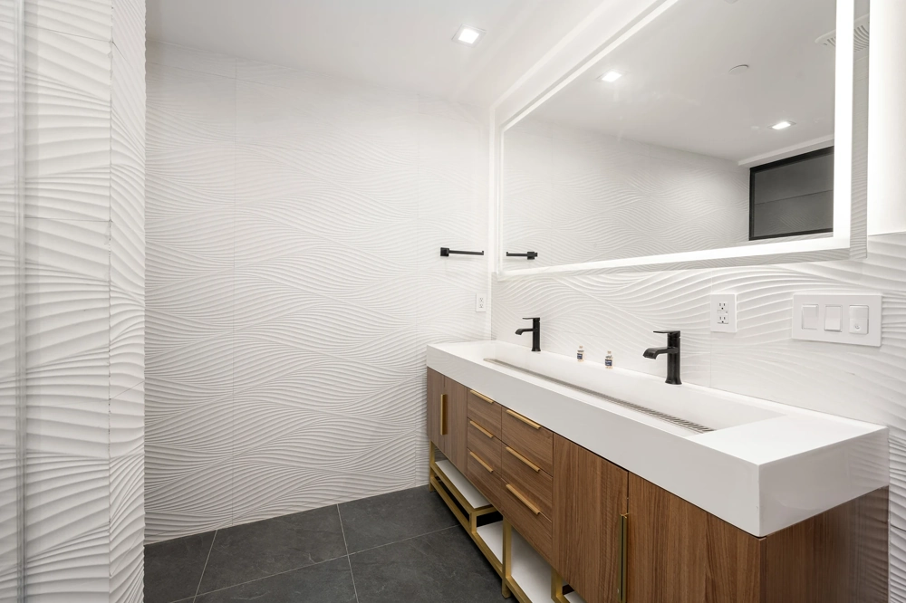 Modernes Badezimmer mit wellenförmigen Wandfliesen, Doppelwaschtisch mit schwarzen Armaturen und Holz-Unterschrank für Badsanierung